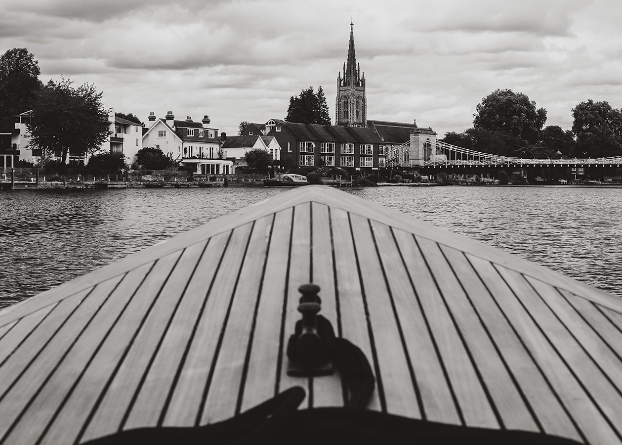 The teak bow of Queen of the Slipstream heading towards All Saints Church and Marlow Suspension Bridge