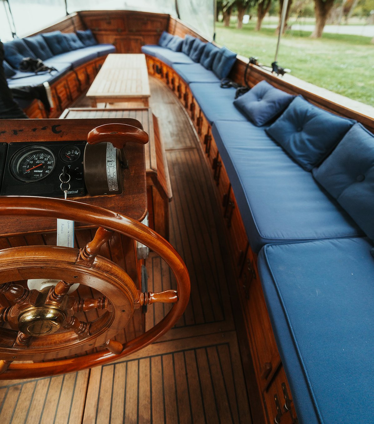 The wooden ship's wheel and long navy banquette seating aboard Queen of the Slipstream